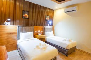 2 camas en una habitación de hotel con sábanas blancas en Raim Hotel en Pagadían​