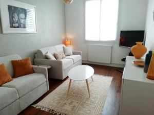 ein Wohnzimmer mit einem Sofa und einem Tisch in der Unterkunft La réserve à bonheurs in Les Sables-dʼOlonne