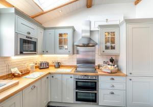 una cucina con armadi bianchi e piano cottura di 2 Browcote Cottage a Ravenscar