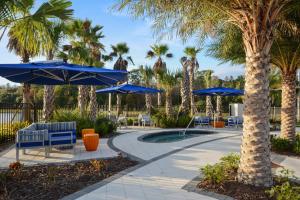 un patio con sombrillas y sillas azules y palmeras en Sonoma Resort 7 Bedroom Vacation Home with Pool 1849, en Kissimmee