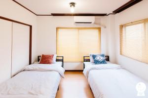 2 Betten in einem Zimmer mit 2 Fenstern in der Unterkunft Urakami #201 / Vacation STAY 41894 in Nagasaki