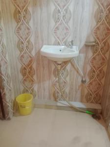 La salle de bains est pourvue d'un lavabo et d'un seau jaune. dans l'établissement Aanand Bhwan, à Ayodhya