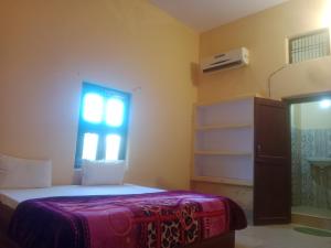 - une petite chambre avec un lit et une fenêtre dans l'établissement Aanand Bhwan, à Ayodhya