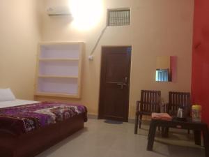 - une chambre avec un lit, une table et une porte dans l'établissement Aanand Bhwan, à Ayodhya