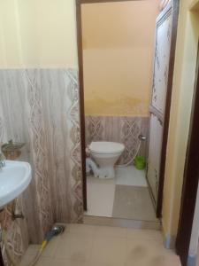 La salle de bains est pourvue de toilettes et d'un lavabo. dans l'établissement Aanand Bhwan, à Ayodhya