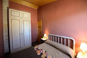 1 dormitorio con 1 cama con paredes de color rosa y puerta en Casa Celeste, en Castelserás