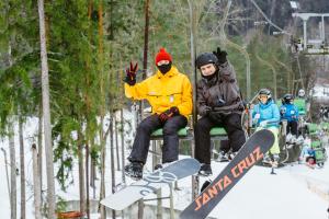 a group of people sitting on a ski lift with snowboards at Kempings Ozolkalns in Cēsis