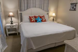 a white bed with red pillows and a blue teddy bear at Beach Front Destin Condo Daily Beach Service - Blue Dolphin in Fort Walton Beach