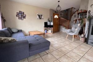 sala de estar con sofá azul y TV en Maison entre lac et montagne en Prunières