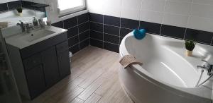 a bathroom with a white tub and a sink at Gîtes BEL'M in La Bresse