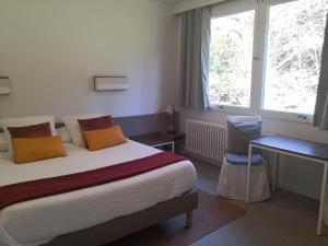 1 dormitorio con cama, escritorio y ventana en Logis Hôtel-Restaurant Le Tanargue, en Valgorge