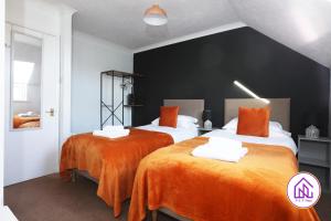 2 camas en una habitación con sábanas de color naranja en Palmers Leaze, Comfortable house close to Aztec West, en Bristol