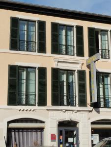 a building with black shuttered windows and a street sign at Hôtel Central in Pau