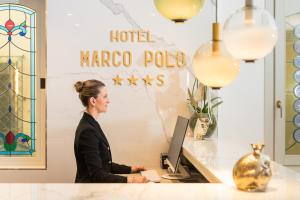 une femme assise sur un bureau avec un ordinateur dans l'établissement Hotel Marco Polo, à Lido di Jesolo