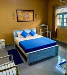 a bedroom with a bed with blue sheets and a window at Dhee Ayurveda Villa in Malabe