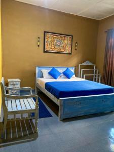 Dhee Ayurveda Villa في Malabe: غرفة نوم بسرير وملاءات زرقاء ومقعد