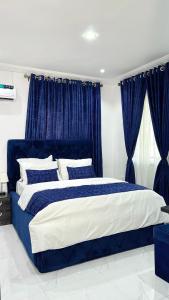 a blue and white bed in a bedroom with blue curtains at Blueocean.cog Apartments in Benin City