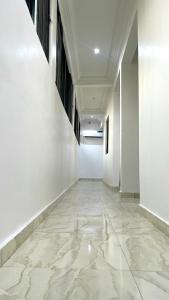 un couloir vide avec des murs blancs et un sol en marbre dans l'établissement Blueocean.cog Apartments, à Benin City