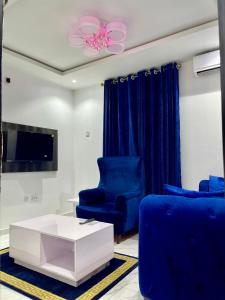 un soggiorno con sedie blu e un tavolo bianco di Blueocean.cog Apartments a Benin City