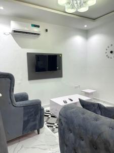 a living room with two chairs and a tv on a wall at Blueocean.cog Apartments in Benin City