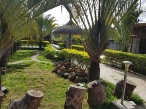 un jardín con una palmera y rocas y una sombrilla en Villas Rocher - Standard Suite 3A en Grand Baie