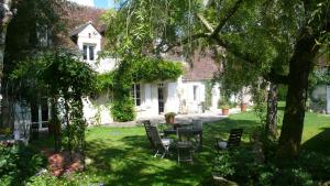 Un jardín con una mesa y sillas frente a una casa. en Hôte Sainte Marie, en Ouchamps