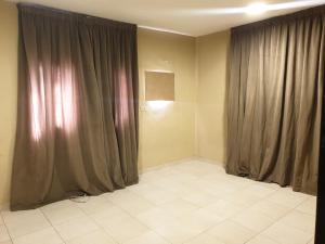 Habitación con cortinas grises y suelo de baldosa blanca. en Apartment for rent, en Dammam