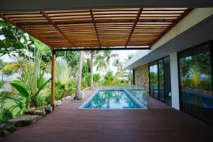 einen Pool in einem Haus mit einer Holzterrasse in der Unterkunft Kiwuki Beachfront Villa in Phu Quoc