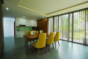 une salle à manger avec une table en bois et des chaises jaunes dans l'établissement Kiwuki Beachfront Villa, à Duong Dong