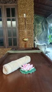 Dhee Ayurveda Villa في Malabe: منشفه وزهره على طاوله