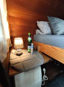 a table with a lamp and a bottle on a bed at Für Alleinreisende-1 Person- Single Room- Rustikales freistehendes Mini Holzfass zum Schlafen, mit angrenzendem Badezimmer! in Leverkusen