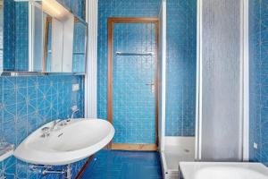Santa Lucia的住宿－Bormio 1，蓝色瓷砖浴室设有水槽和淋浴