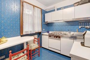 a kitchen with white cabinets and blue tiles at Bormio 1 in Santa Lucia