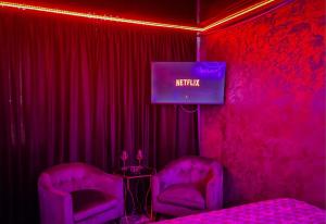 a room with two purple chairs and a tv at JACUZZl & LOVE in Bucharest