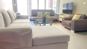 a living room with white couches and a tv at Ausmine Sydney CBD 2Bedroom Apt in Sydney
