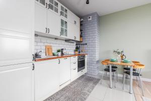 a kitchen with white cabinets and a wooden table at SuperApart Sowińskiego 53e in Warsaw