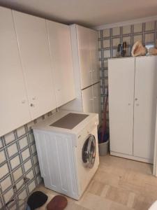 uma máquina de lavar roupa numa cozinha com armários brancos em Comfortable apartment 200 m from the sea em Piraeus