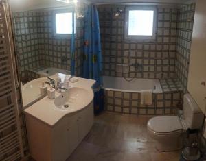 uma casa de banho com um lavatório, uma banheira e um WC. em Comfortable apartment 200 m from the sea em Piraeus