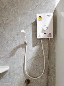 uma casa de banho com um chuveiro eléctrico branco na parede em Tokyo Hotel em Nakhon Ratchasima