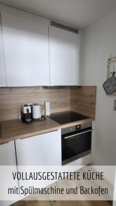 a kitchen with white cabinets and a stove top oven at Ferienwohnung Bergzeit mit Pool und Sauna in Missen-Wilhams
