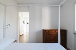 a bedroom with a white bed and a wooden dresser at ABC affittacamere in Celle Ligure