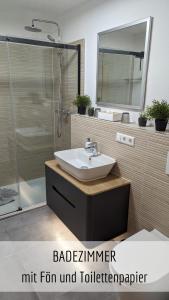 a bathroom with a sink and a shower with a mirror at Ferienwohnung Bergzeit mit Pool und Sauna in Missen-Wilhams