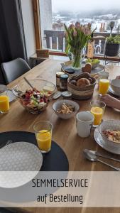 una mesa de madera con productos para el desayuno y zumo de naranja en Ferienwohnung Bergzeit mit Pool und Sauna en Missen-Wilhams