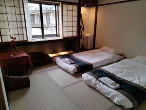 2 camas en una habitación con ventana en 秋桜館Cosmos en Kioto
