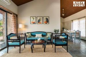 ナーシクにあるStayVista's Cerenity Castle - Lakeside Haven with Hill-View, Terrace & Indoor Entertainmentのソファと椅子とテーブルのあるリビングルーム