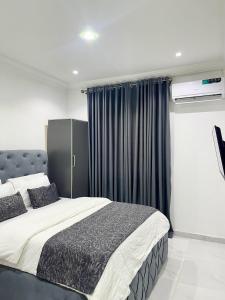 sypialnia z dużym łóżkiem z niebieskimi zasłonami w obiekcie Blueocean.cog Apartments w mieście Benin City
