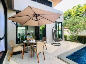 een tafel en stoelen met een parasol naast een zwembad bij Luxurious Zen Pool Villa in Nai Harn Beach