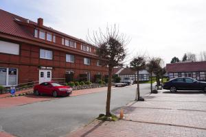 a street with two cars parked in front of a building at Alcor Hotel Feriendorf an der Ostsee in Wohlenberg