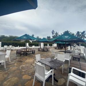 a patio with tables and chairs and umbrellas at The Beach House by Maasai in Mombasa