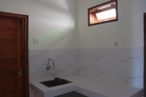 a white kitchen with a sink and a window at Griya Mozaik in Jimbaran